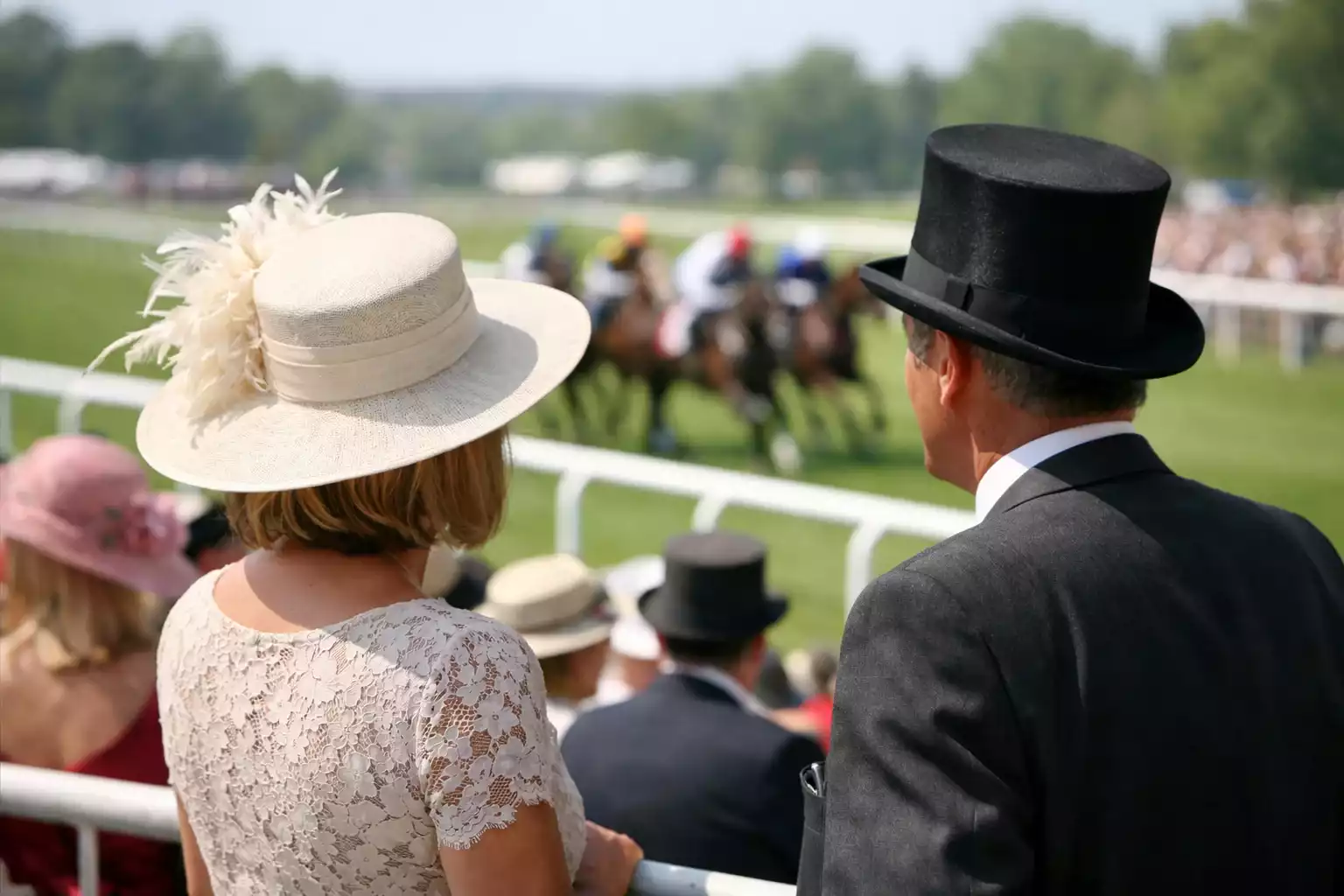 Elegant gekleed publiek bij een prestigieus paardensportevenement met renbaan op achtergrond